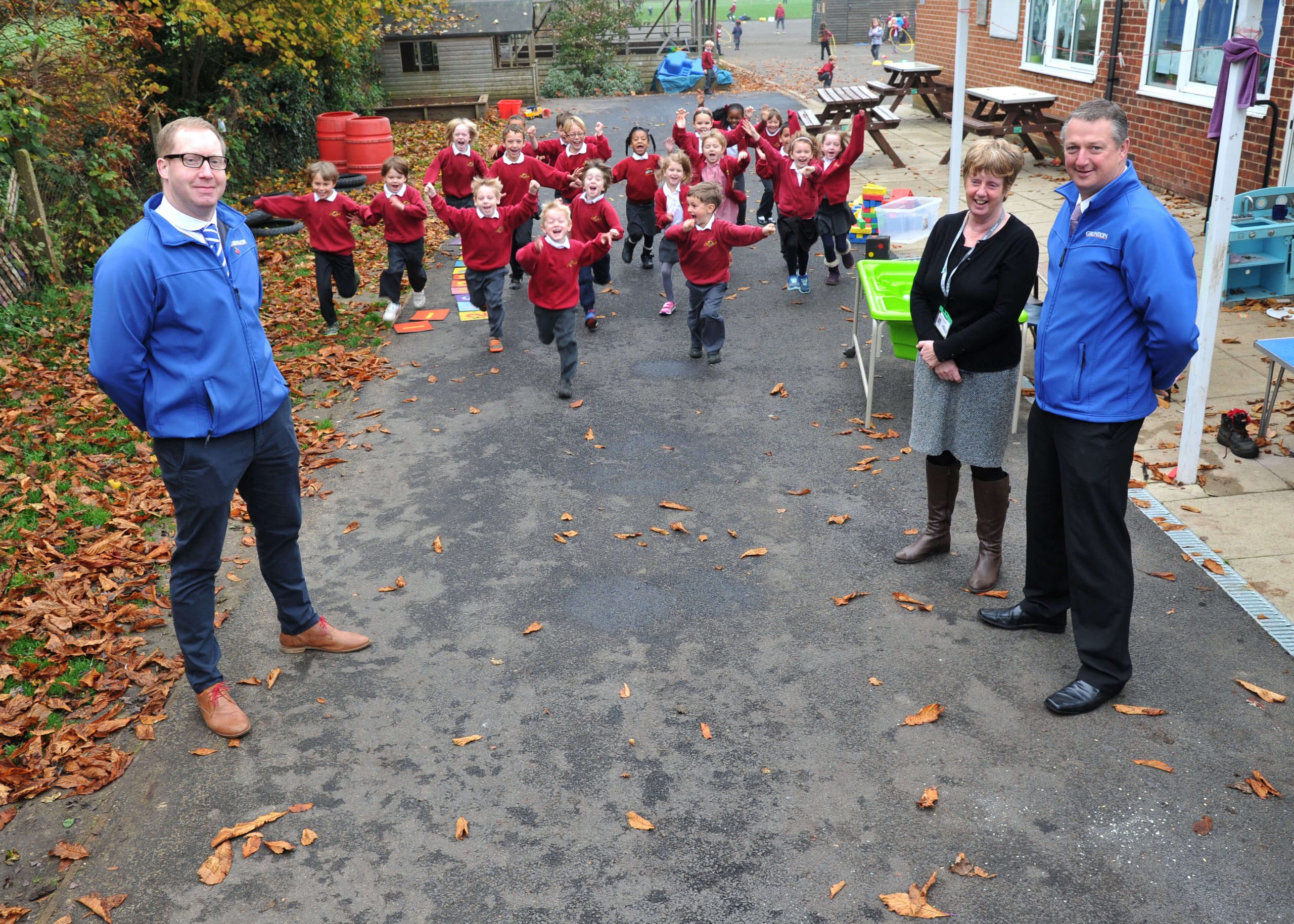 Pupils at the school having fun on the new play and learning area, watched by Jamie Brooks (left), regional materials recovery facility manager for Grundon, whose children attend the school, together with headteacher Heather Haigh and Andy Bright, deputy aggregates manager, Grundon Sand &amp; Gravel.